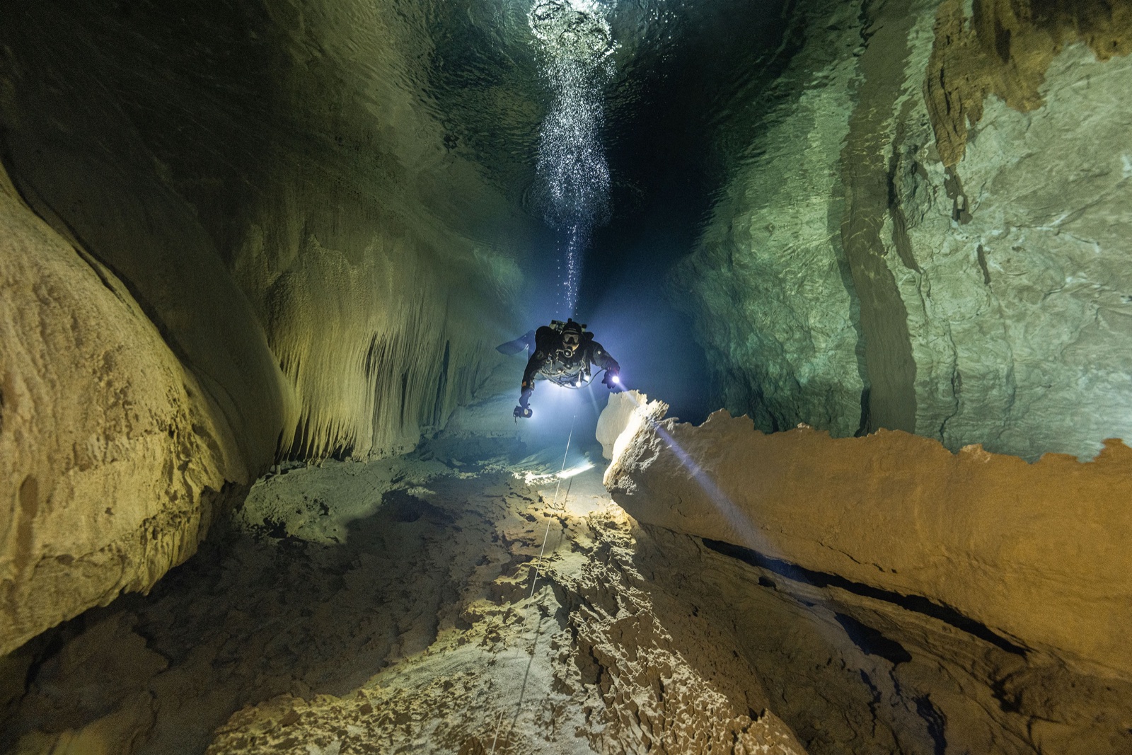 Imad Farhat GUE cave diver in narrow passage with stalactites and primary light beam