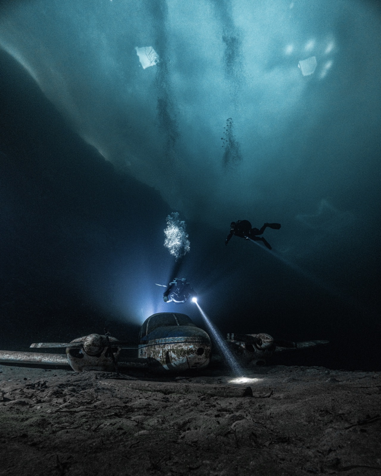 Two GUE ice divers above Flintkote aircraft wreck under ice ceiling Canada