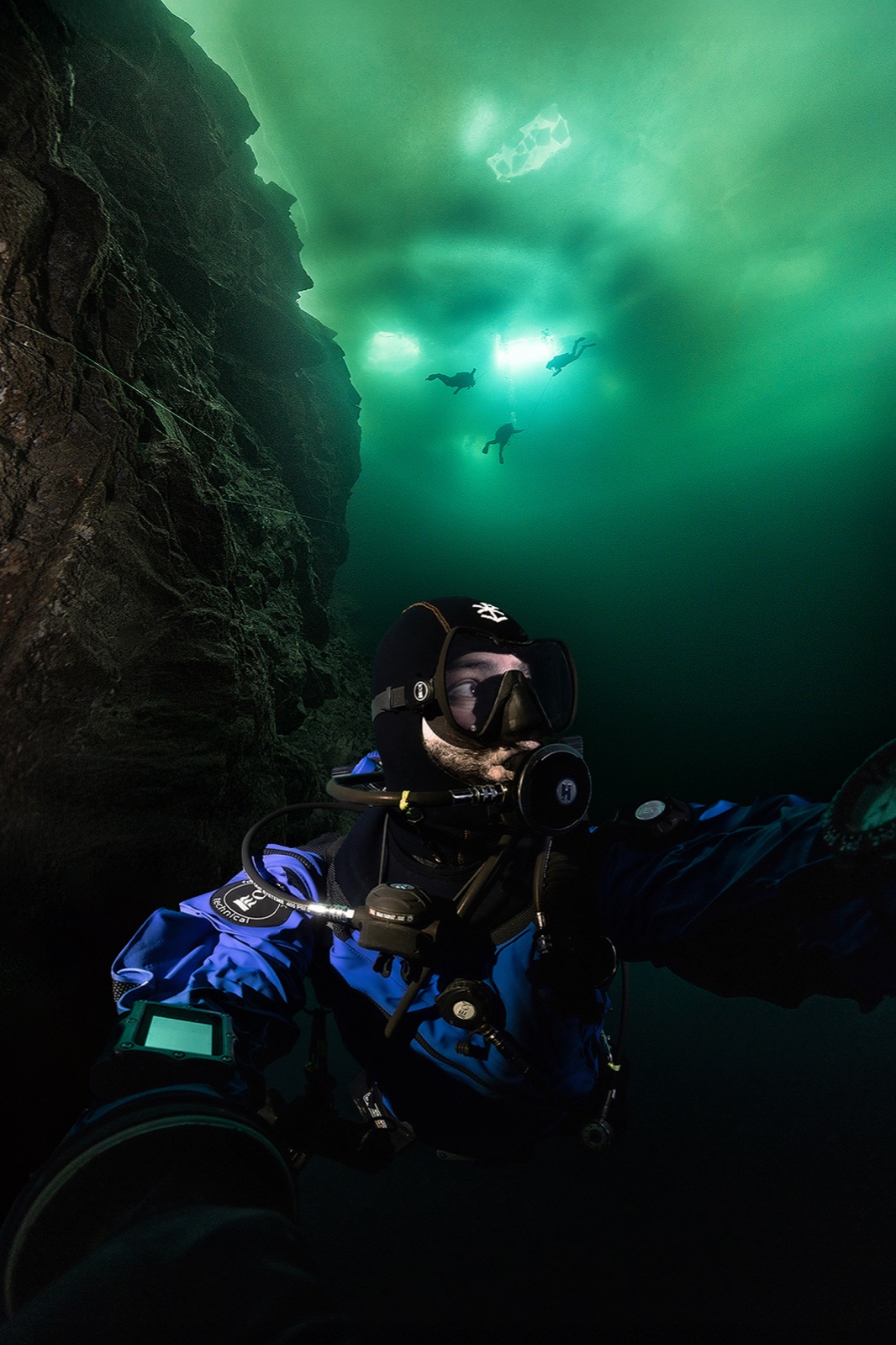 Underwater portrait of Imad Farhat ice diving at Flintkote Canada with team above